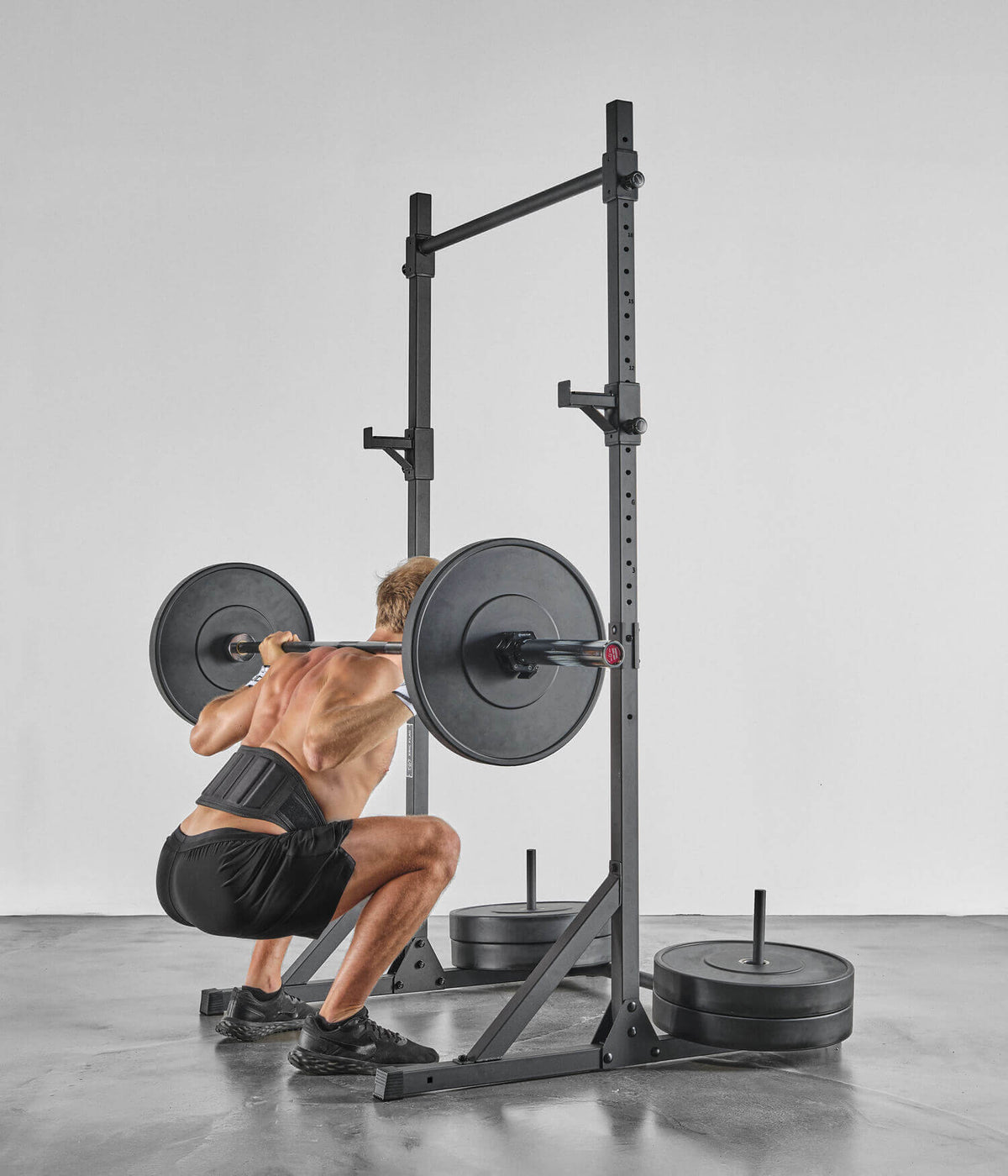 Homme s'entraînant avec Colonnes de Stabilisation - Barre de Traction et poids, en pleine squat.