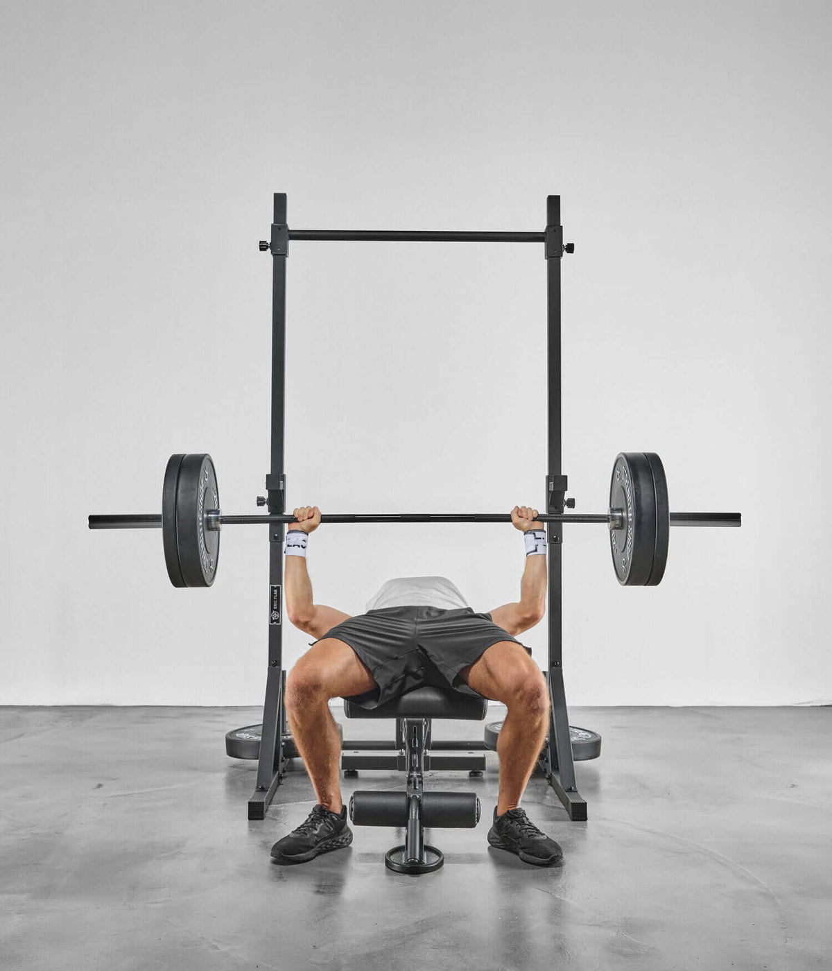 Person lifting weights using Colonnes de Stabilisation - Barre de Traction in a gym setting.